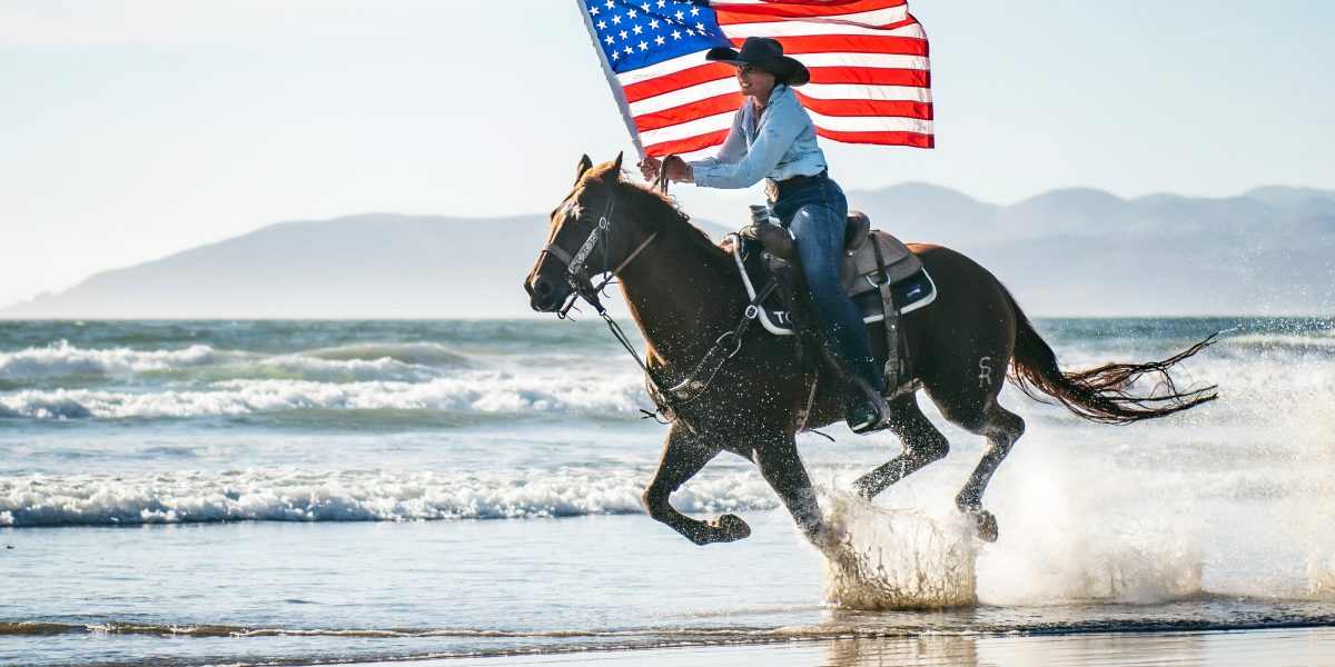 jinete en la playa con bandera americana